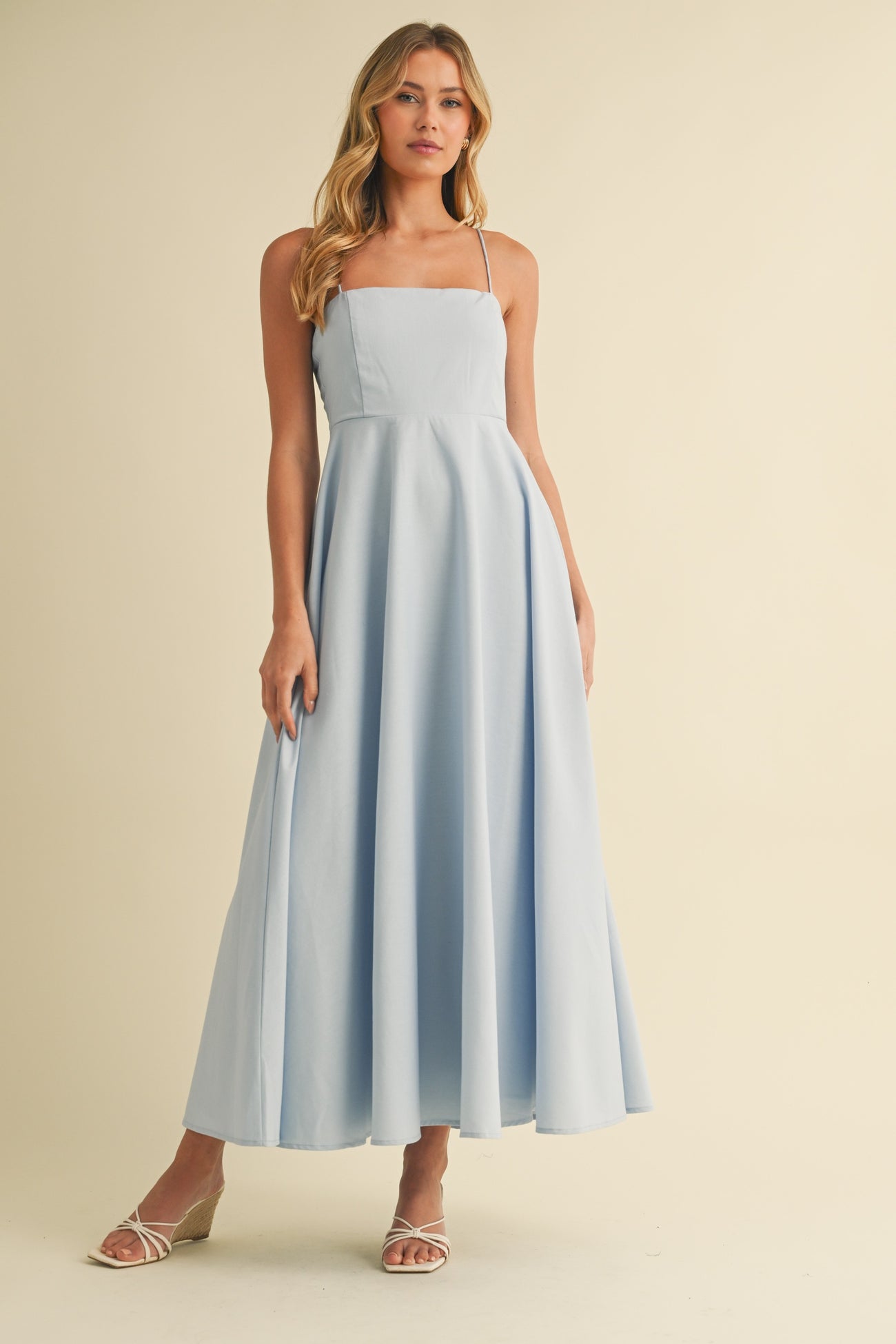 woman wearing a light blue spaghetti strap maxi dress with a fitted bodice and flowy skirt