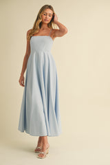 woman wearing a light blue spaghetti strap maxi dress with a fitted bodice and flowing skirt