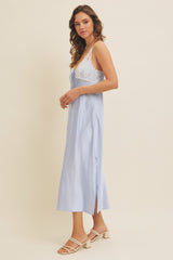 woman wearing a light blue sleeveless midi dress with lace details and a side slit
