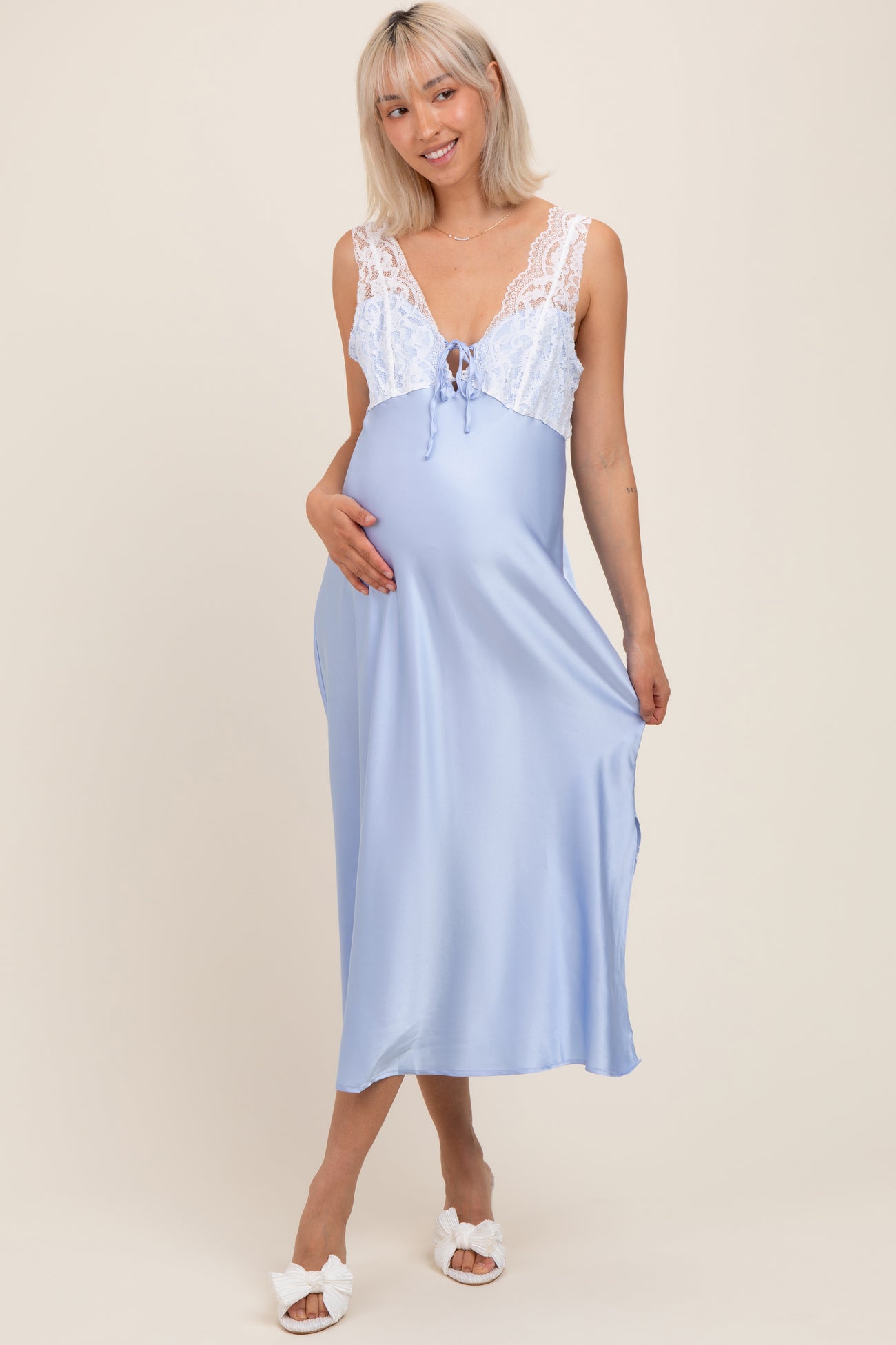 woman wearing a light blue maternity nightgown with lace detailing and holding her baby bump