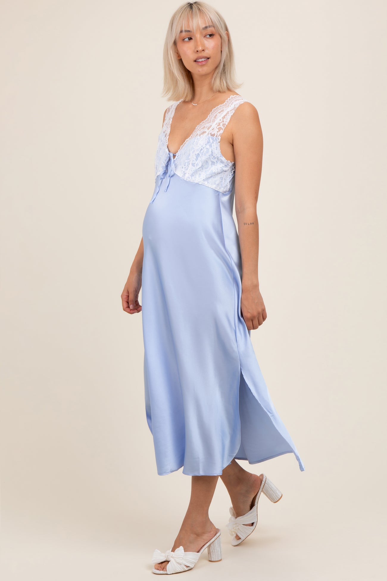 woman wearing a light blue maternity nightgown with lace detailing and a baby bump visible