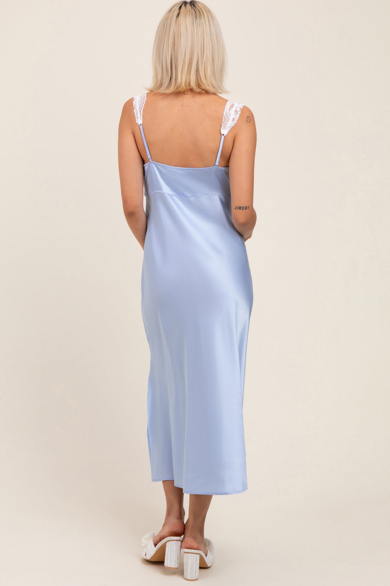 woman wearing a light blue maternity slip dress with lace straps, showing her back and falling to mid-calf