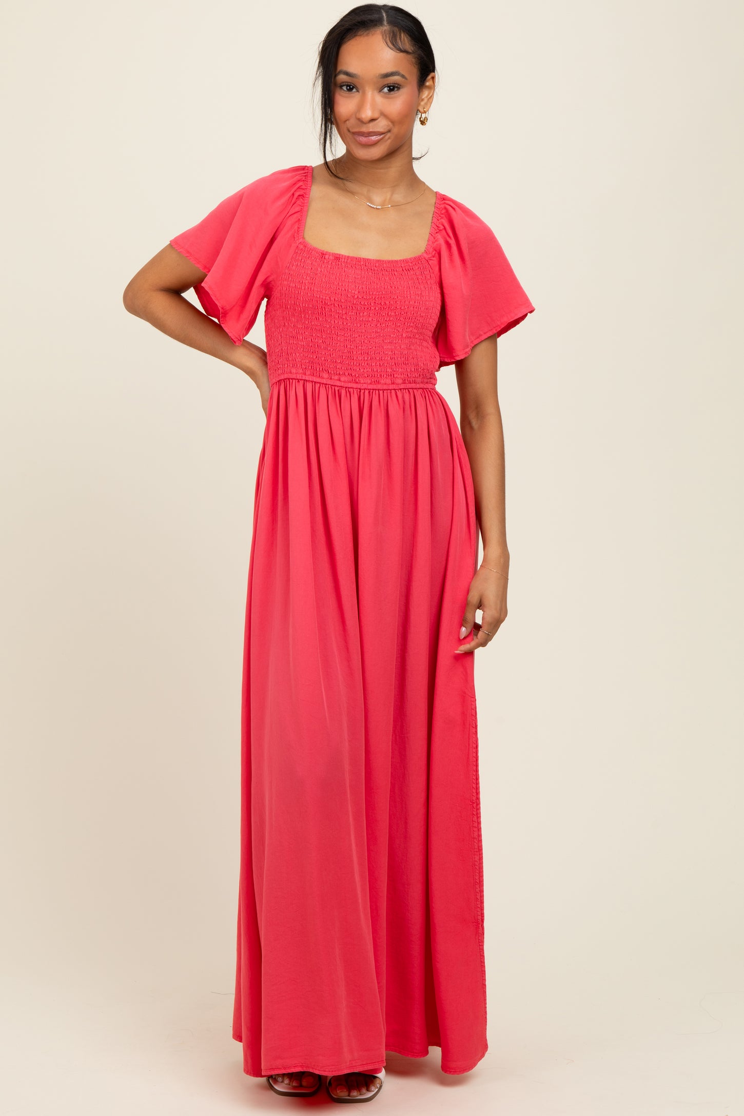 woman wearing a coral maxi dress with a square neckline and short flutter sleeves
