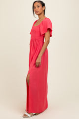 woman wearing a coral maxi dress with a smocked bodice and flutter sleeves, featuring a side slit