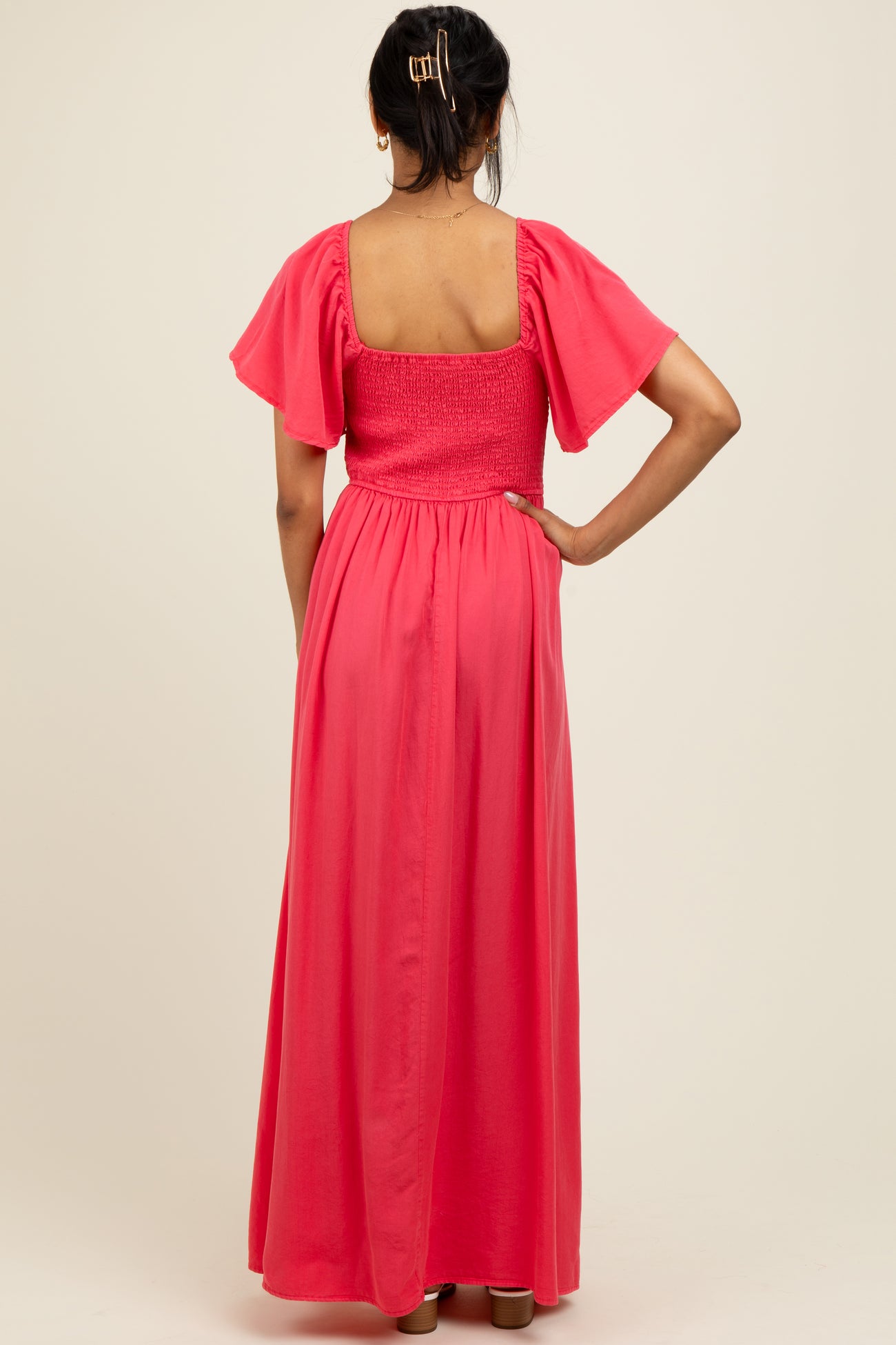 woman wearing a back view of a pink maxi dress with puff sleeves and a smocked bodice