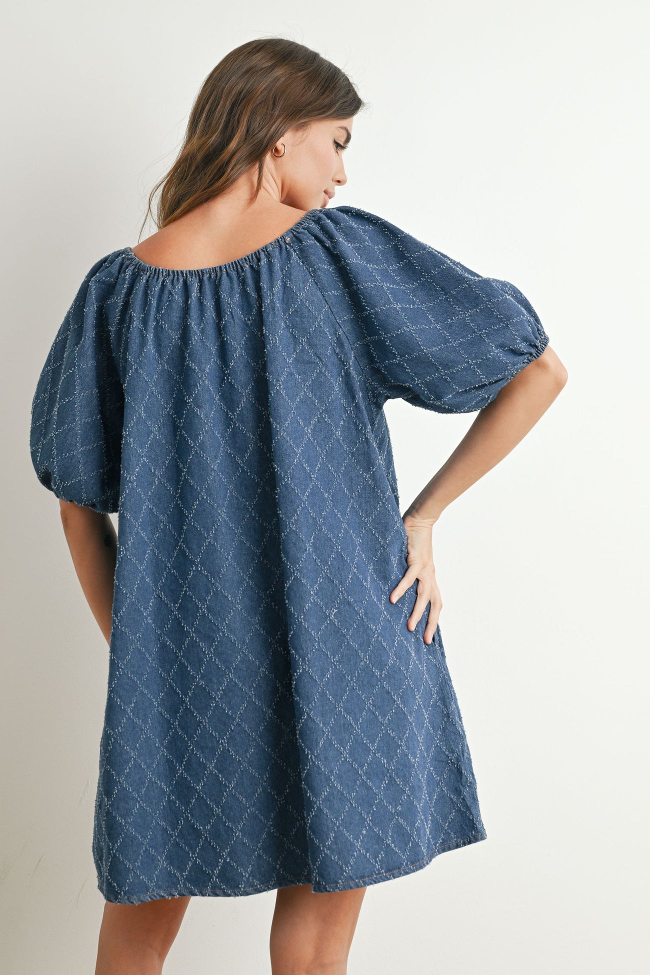 woman wearing a navy blue puff sleeve dress with a relaxed fit and diamond pattern, shown from the back