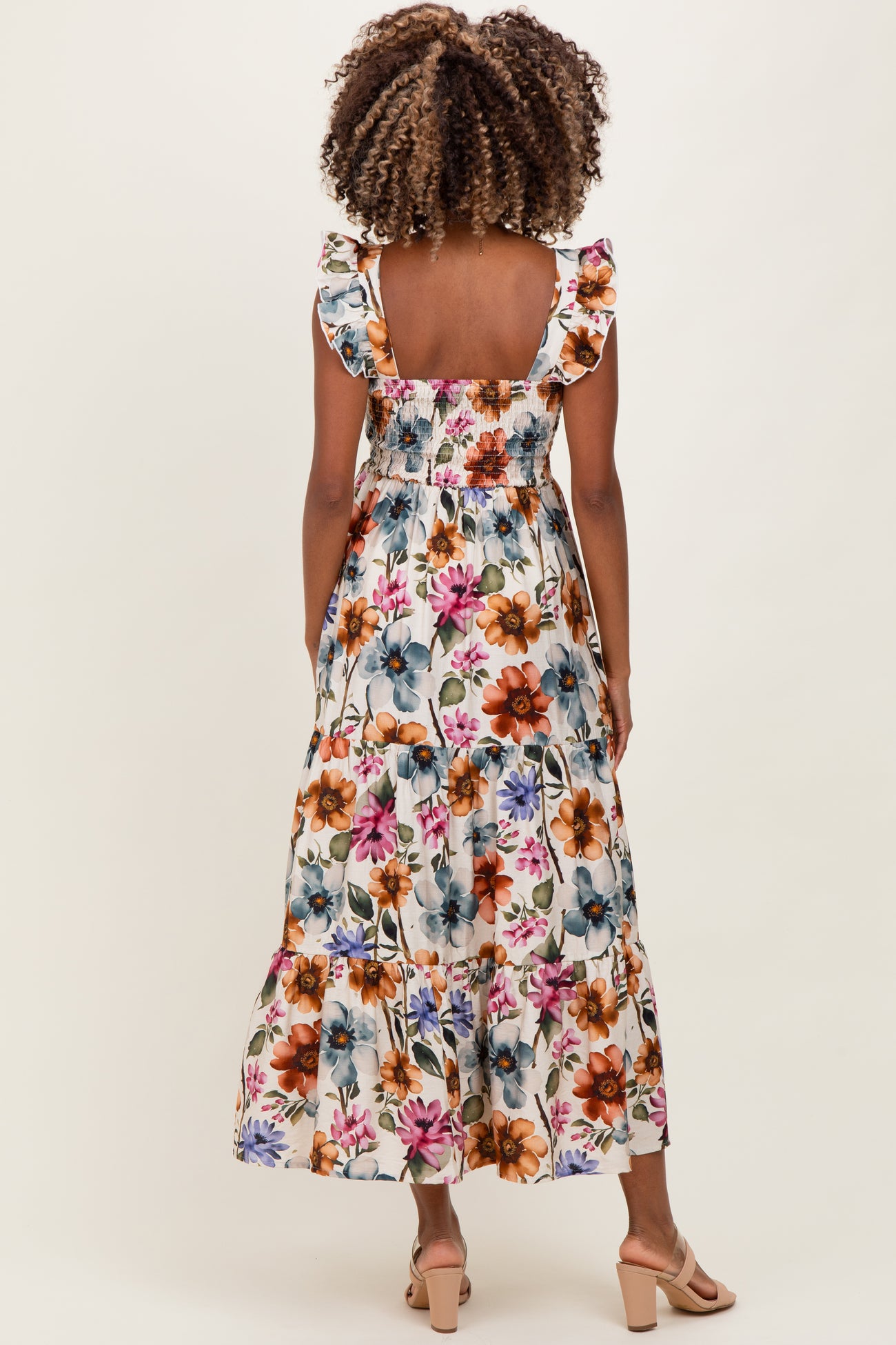 woman wearing a floral print maternity maxi dress with ruffled straps and a smocked bodice, showing a baby bump