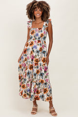woman wearing a floral print maternity maxi dress with ruffle straps and tiered skirt, smiling with a baby bump visible