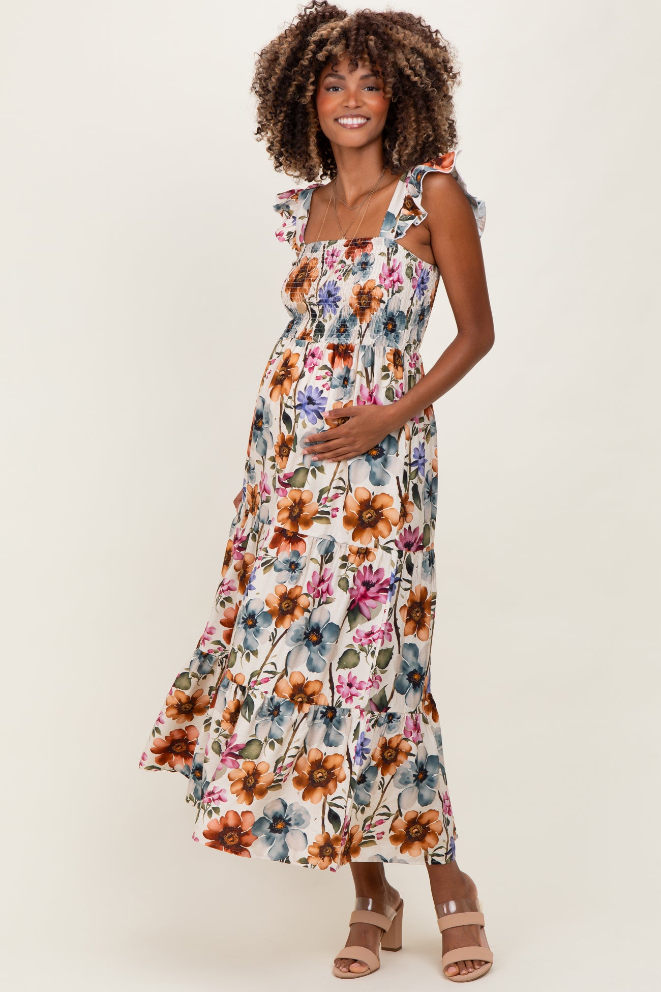 woman wearing a floral maternity maxi dress with ruffled straps and holding her baby bump