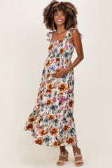 woman wearing a floral maternity maxi dress with ruffled straps and holding her baby bump