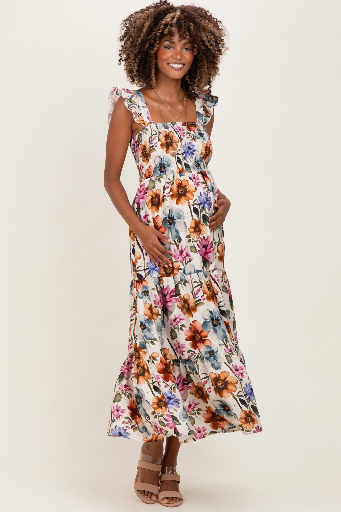 woman wearing a floral print maternity maxi dress with ruffled straps and a visible baby bump