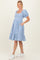 woman wearing a blue gingham maternity dress with puff sleeves and pockets, showing her baby bump