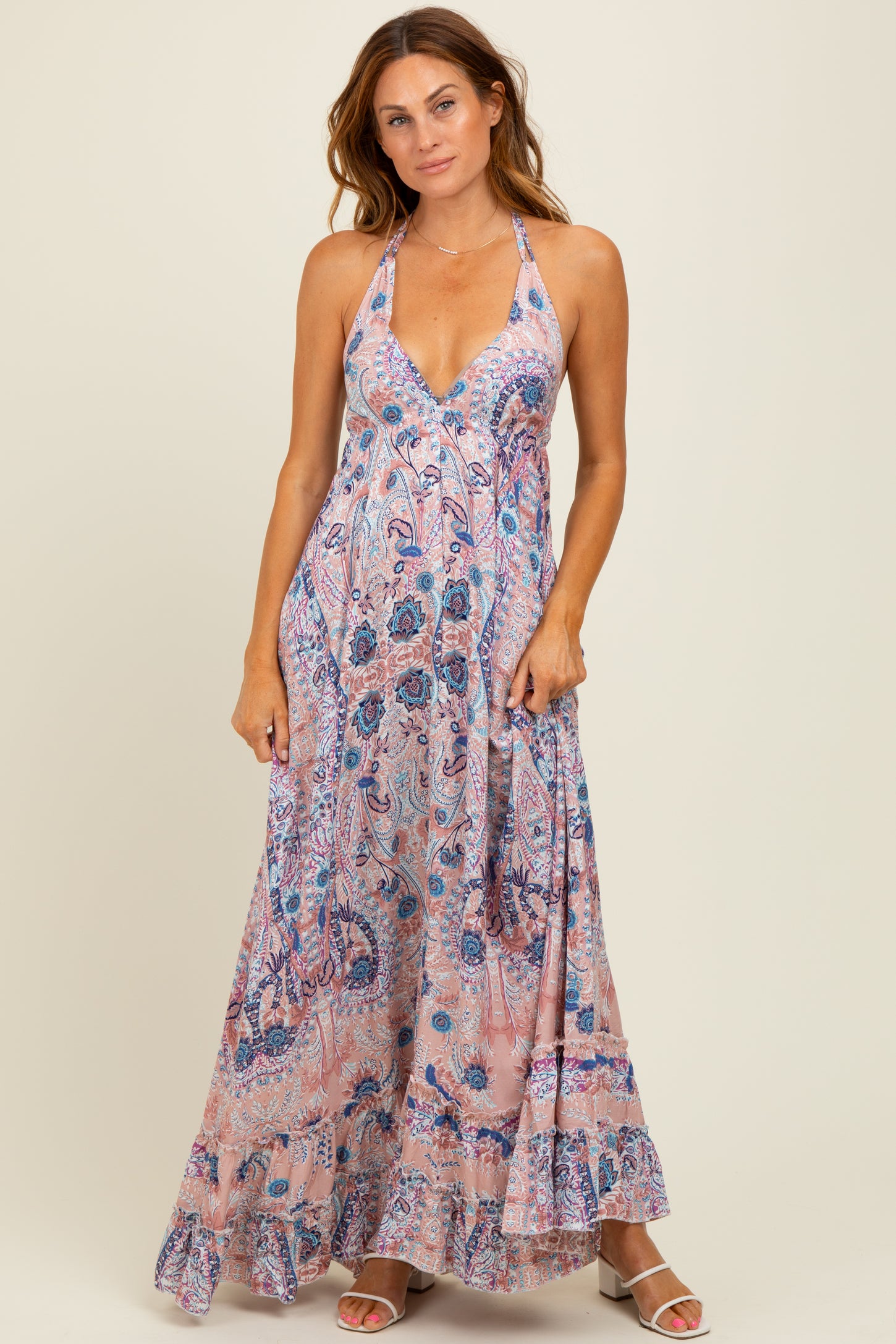 woman wearing a flowy pink paisley maxi dress with a halter neckline and ruffled hem