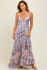 woman wearing a flowy pink paisley maxi dress with a halter neckline and ruffled hem