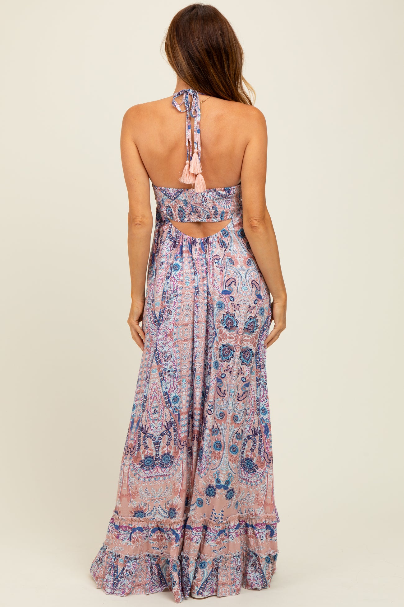 woman wearing a pink and blue patterned maxi dress with a halter neck and open back detail
