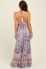 woman wearing a pink and blue patterned maxi dress with a halter neck and open back detail