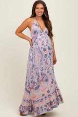 woman wearing a pink and purple paisley print maternity maxi dress with a halter neck and ruffled hem, showing her baby bump