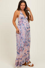 woman wearing a patterned halter maternity maxi dress with a flowing skirt and a visible baby bump