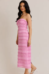 woman wearing a strapless hot pink midi dress with textured detailing and a fitted silhouette