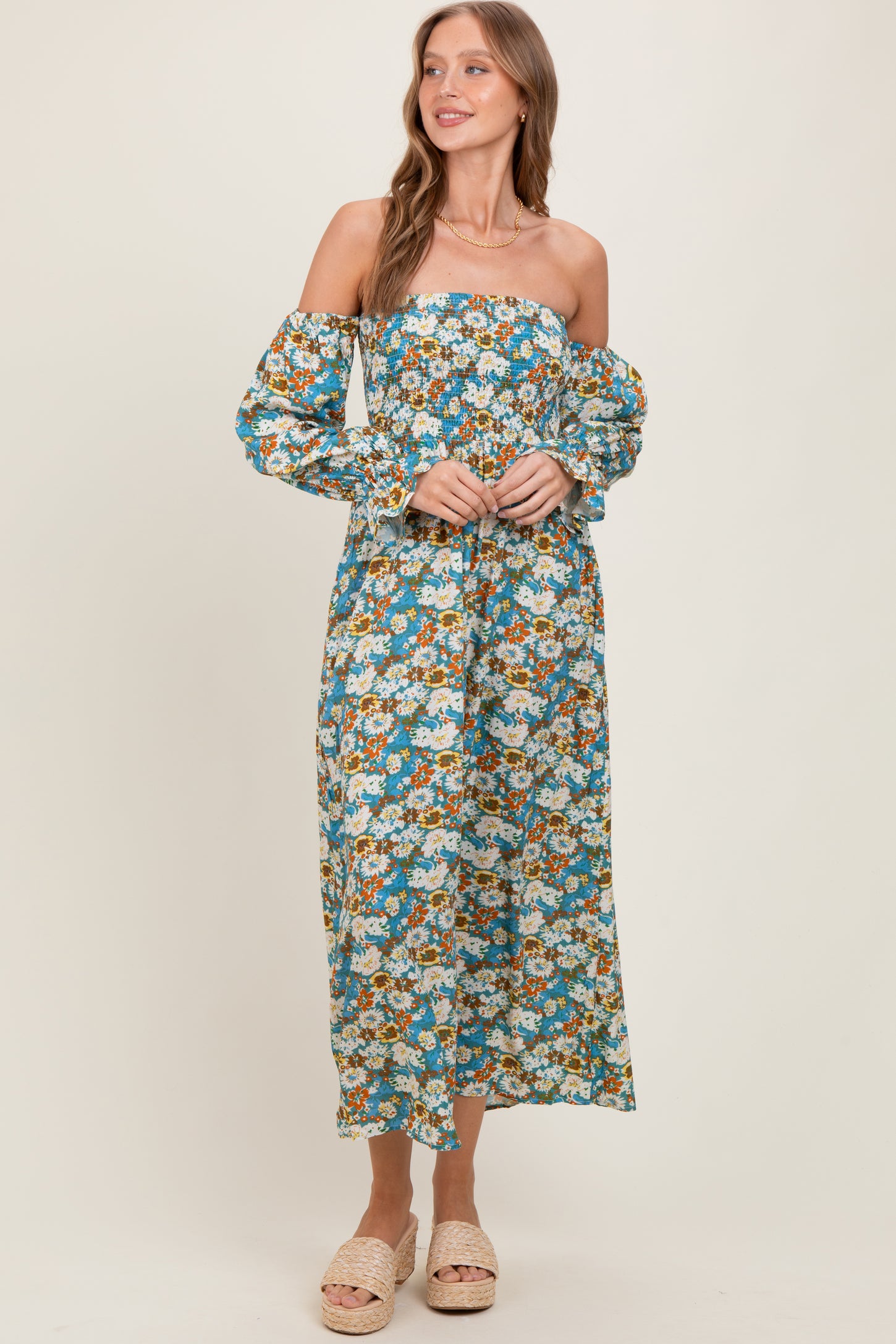 woman wearing a floral off-shoulder maxi dress with long sleeves and a cinched waist