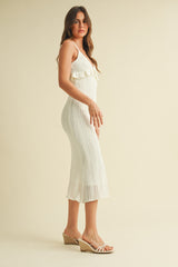 woman wearing a white knitted midi dress with ruffle details and paired with wedge sandals