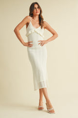 woman wearing a cream knitted midi dress with ruffle details and spaghetti straps, standing against a light background