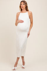 woman wearing a white sleeveless maternity dress with a ribbed texture and holding her baby bump
