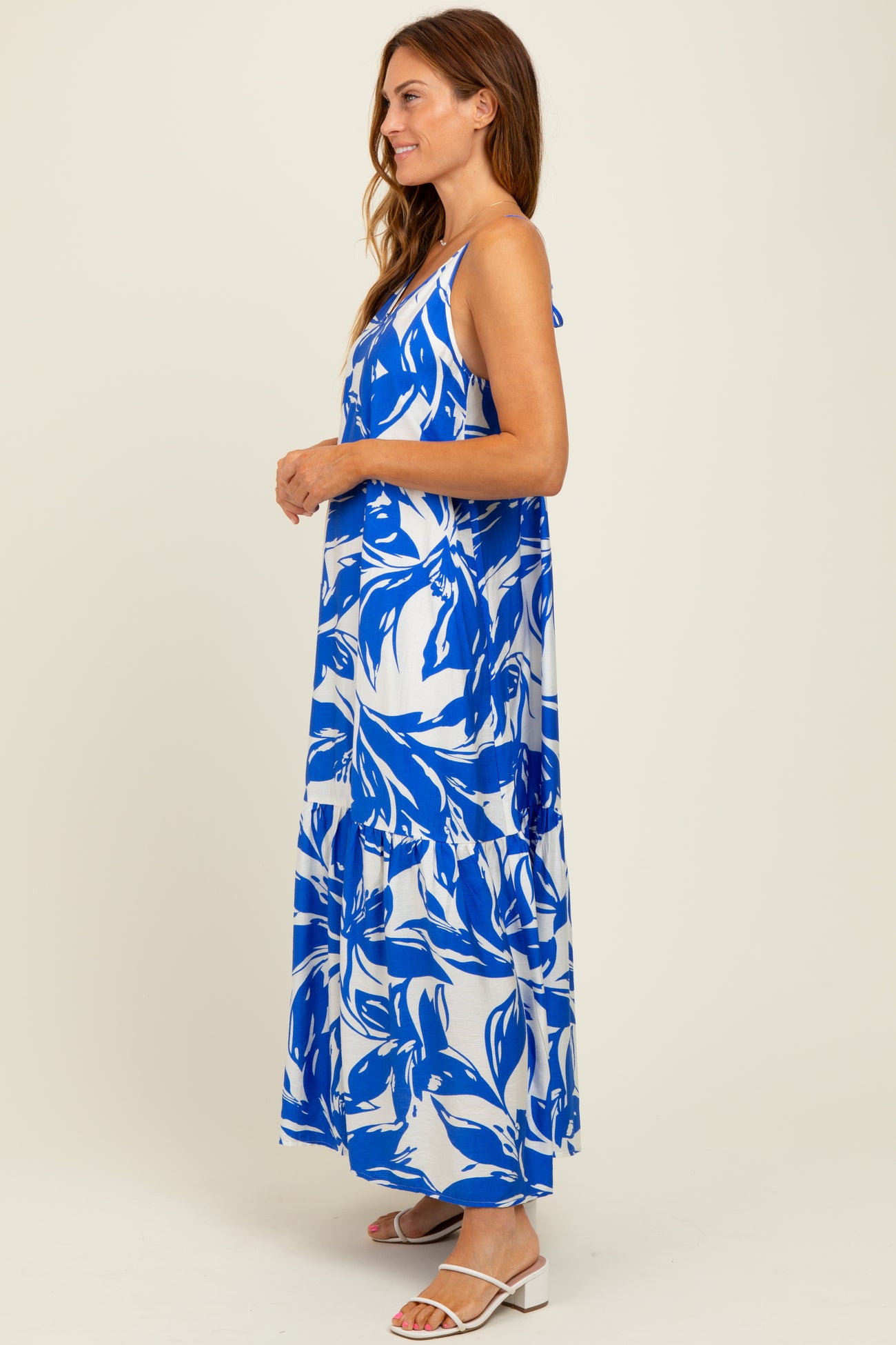 woman wearing a blue and white floral maxi dress with adjustable straps and a flowy silhouette