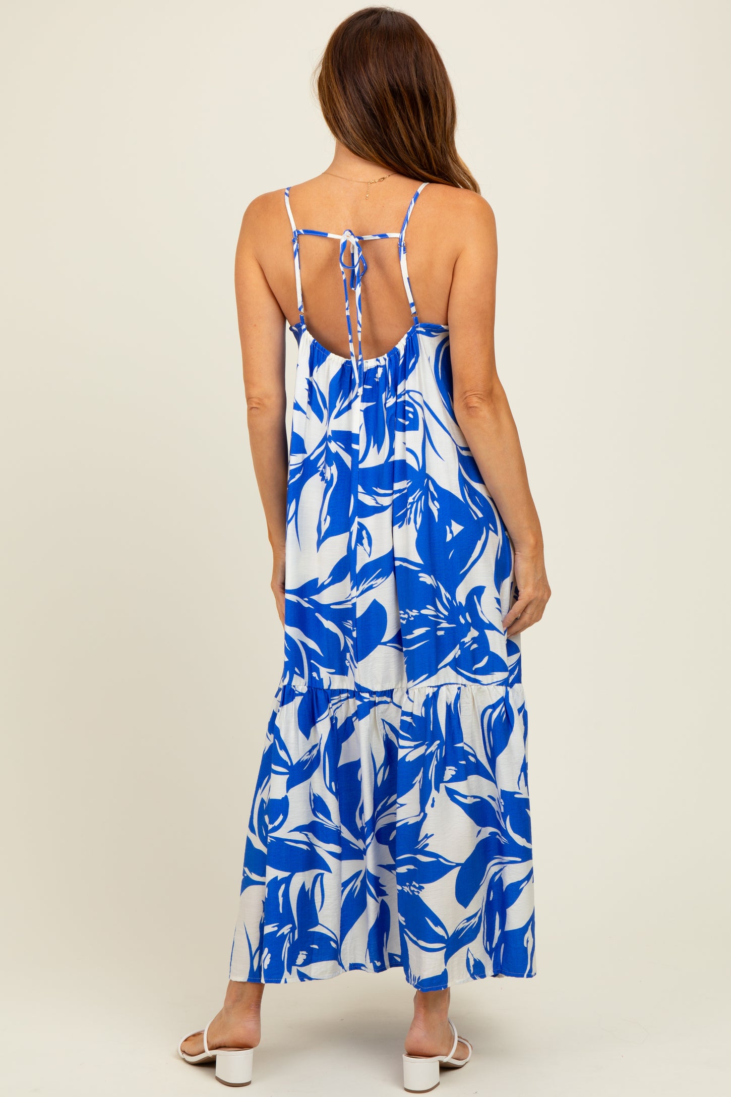 woman wearing a blue and white floral maxi dress with a tie back and tiered skirt