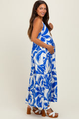 woman wearing a blue and white floral maternity maxi dress, showing her baby bump and paired with white sandals