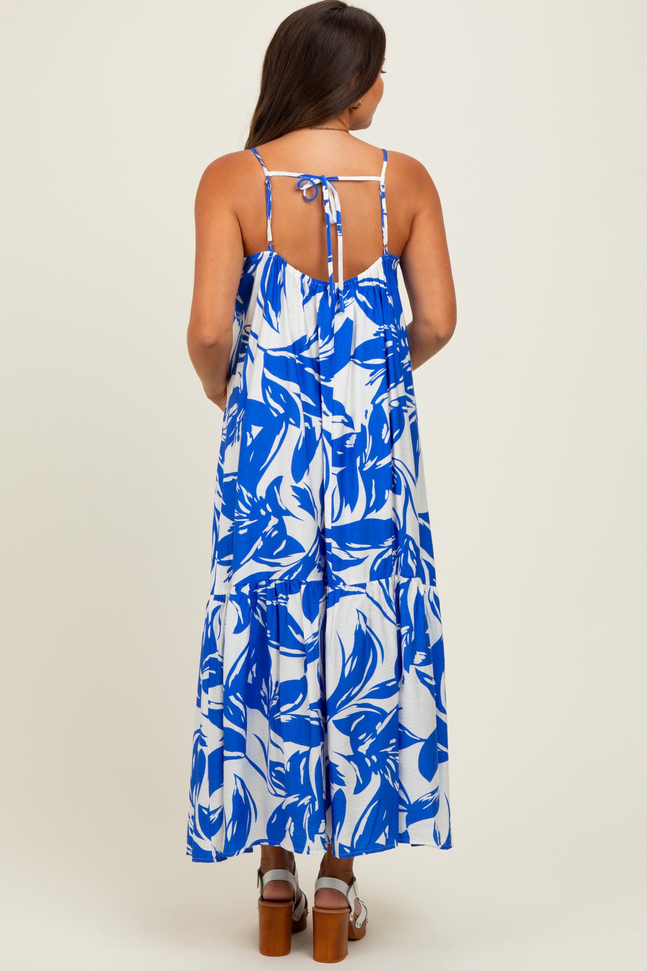 woman wearing a blue and white floral maternity maxi dress with a tie back and flowy skirt