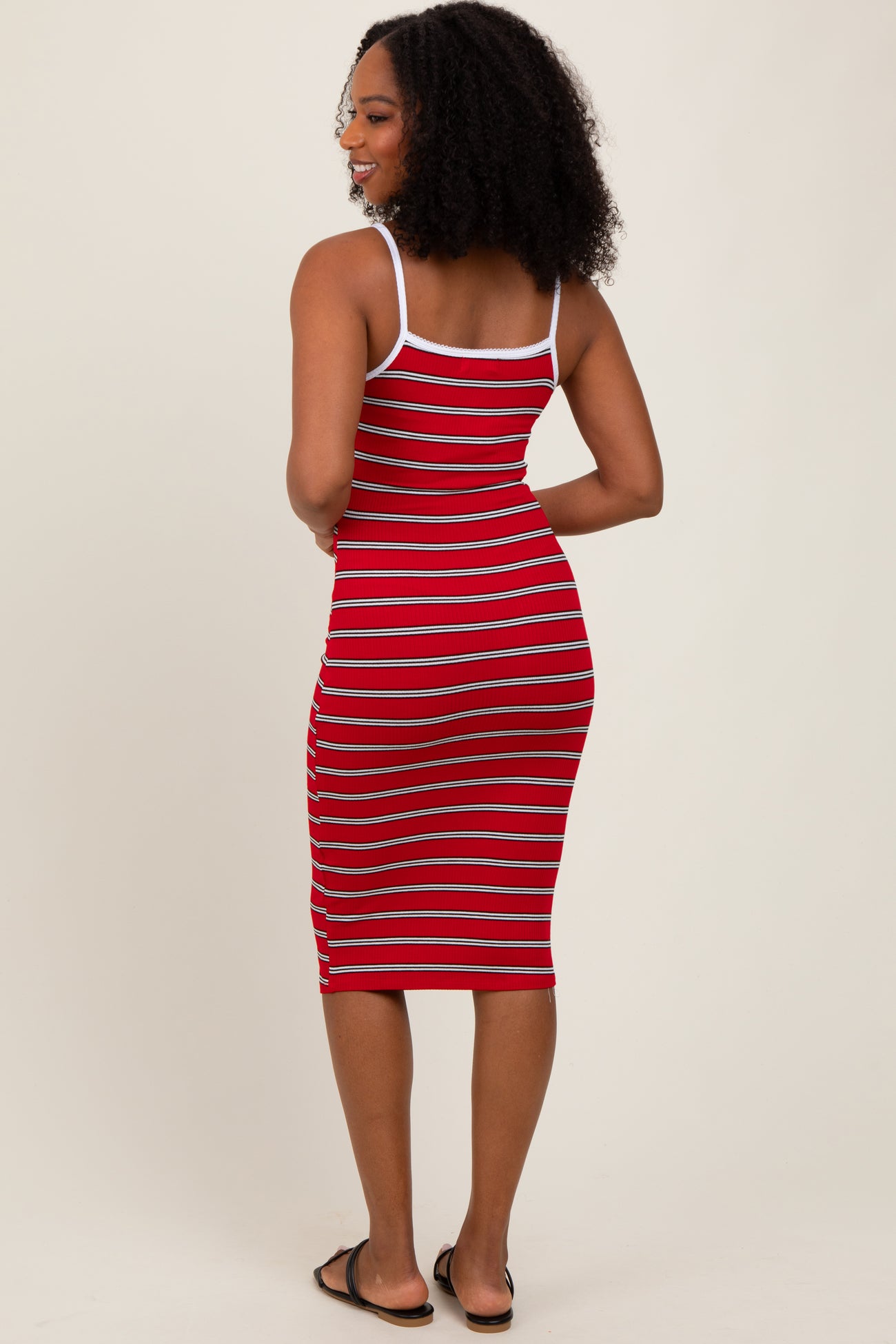 woman wearing a red and white striped midi dress with thin shoulder straps and a fitted silhouette