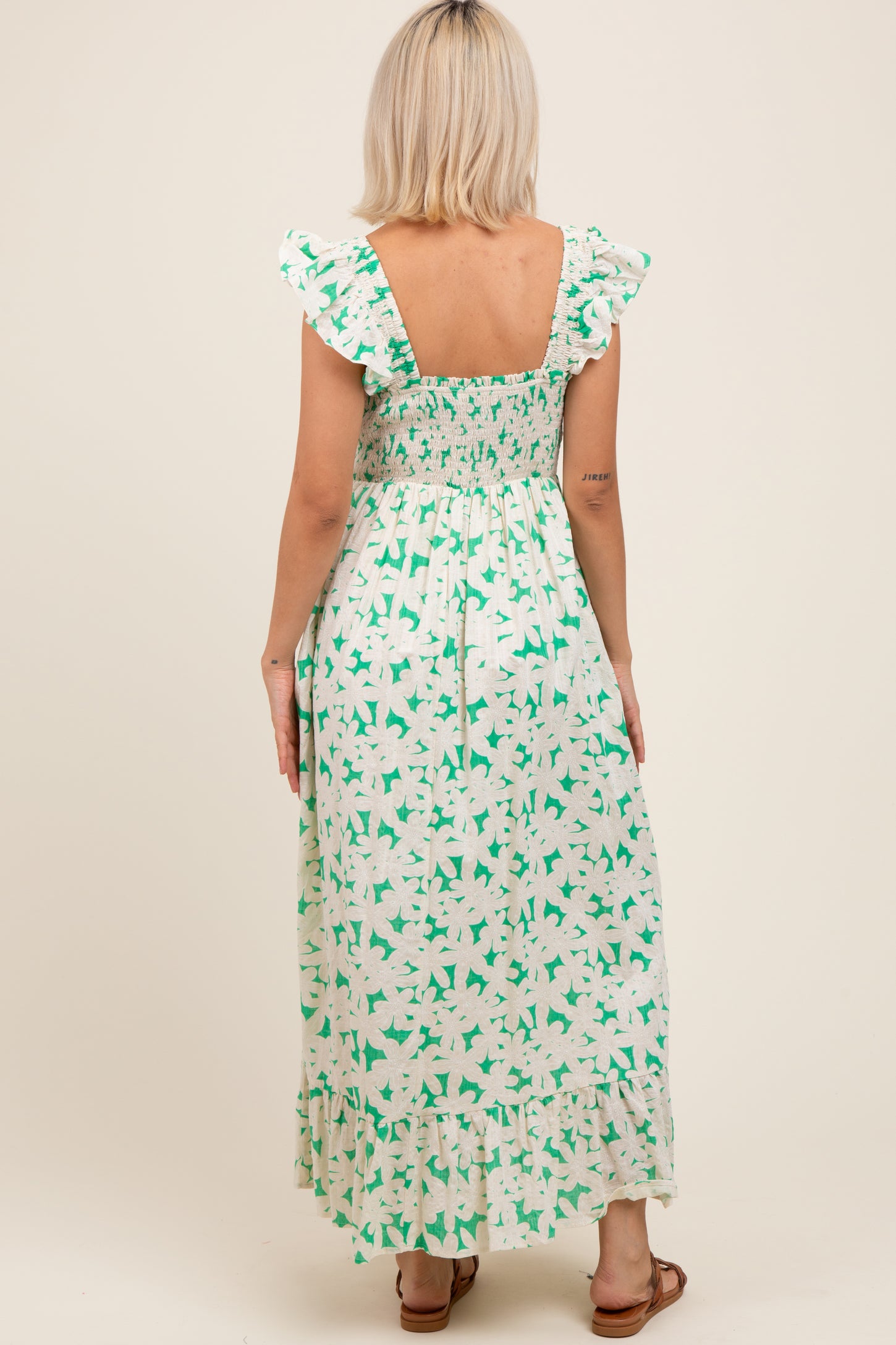 woman wearing a green and white floral maternity maxi dress with ruffled sleeves and a smocked back