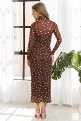 woman wearing a brown polka dot sheer long sleeve dress with a form-fitting silhouette, standing with her back to the camera