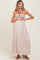 woman wearing a beige strapless maternity maxi dress holding her baby bump