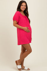 woman wearing a pink short sleeve maternity dress, holding her baby bump with a relaxed fit and tie detail