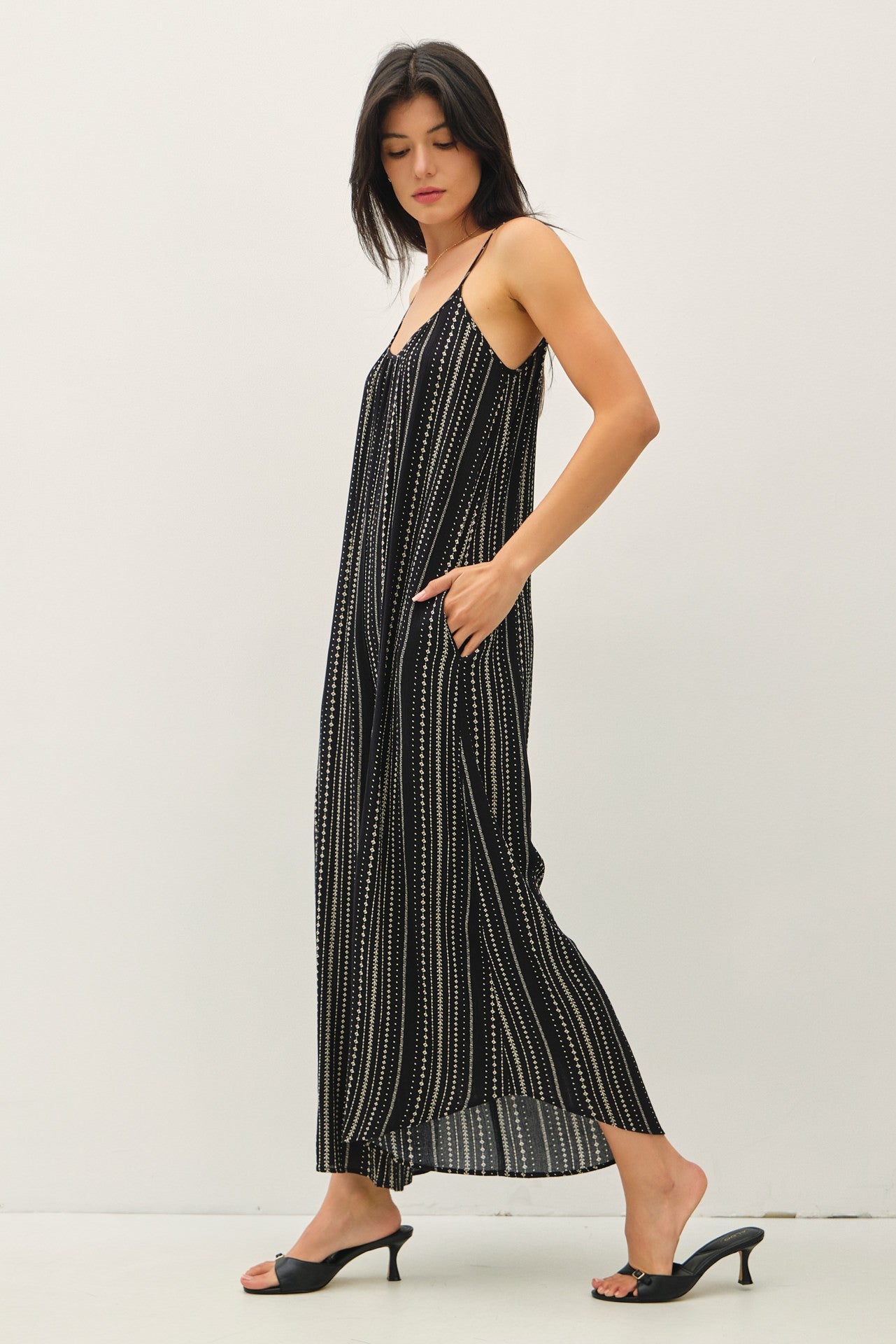 woman wearing a black and white striped maxi dress with thin straps and side pockets