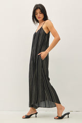 woman wearing a black and white striped maxi dress with thin straps and side pockets