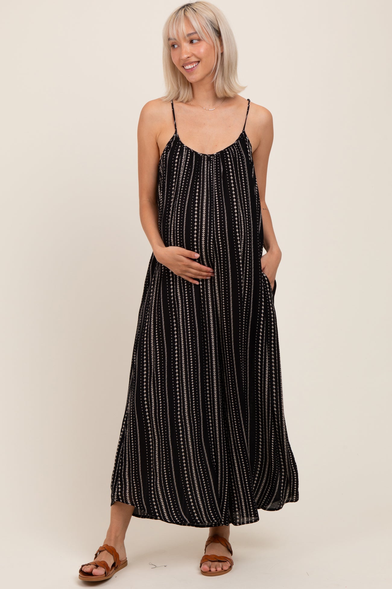 woman wearing a black and white striped maternity maxi dress with a flowing silhouette and pockets, highlighting her baby bump