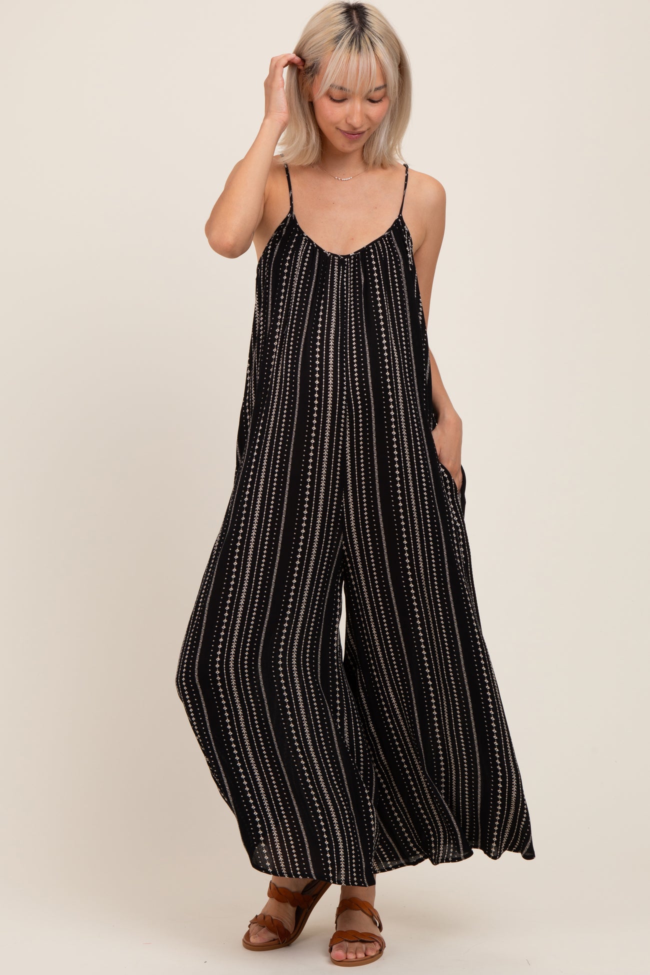 woman wearing a black and white striped maternity jumpsuit with wide legs and pockets