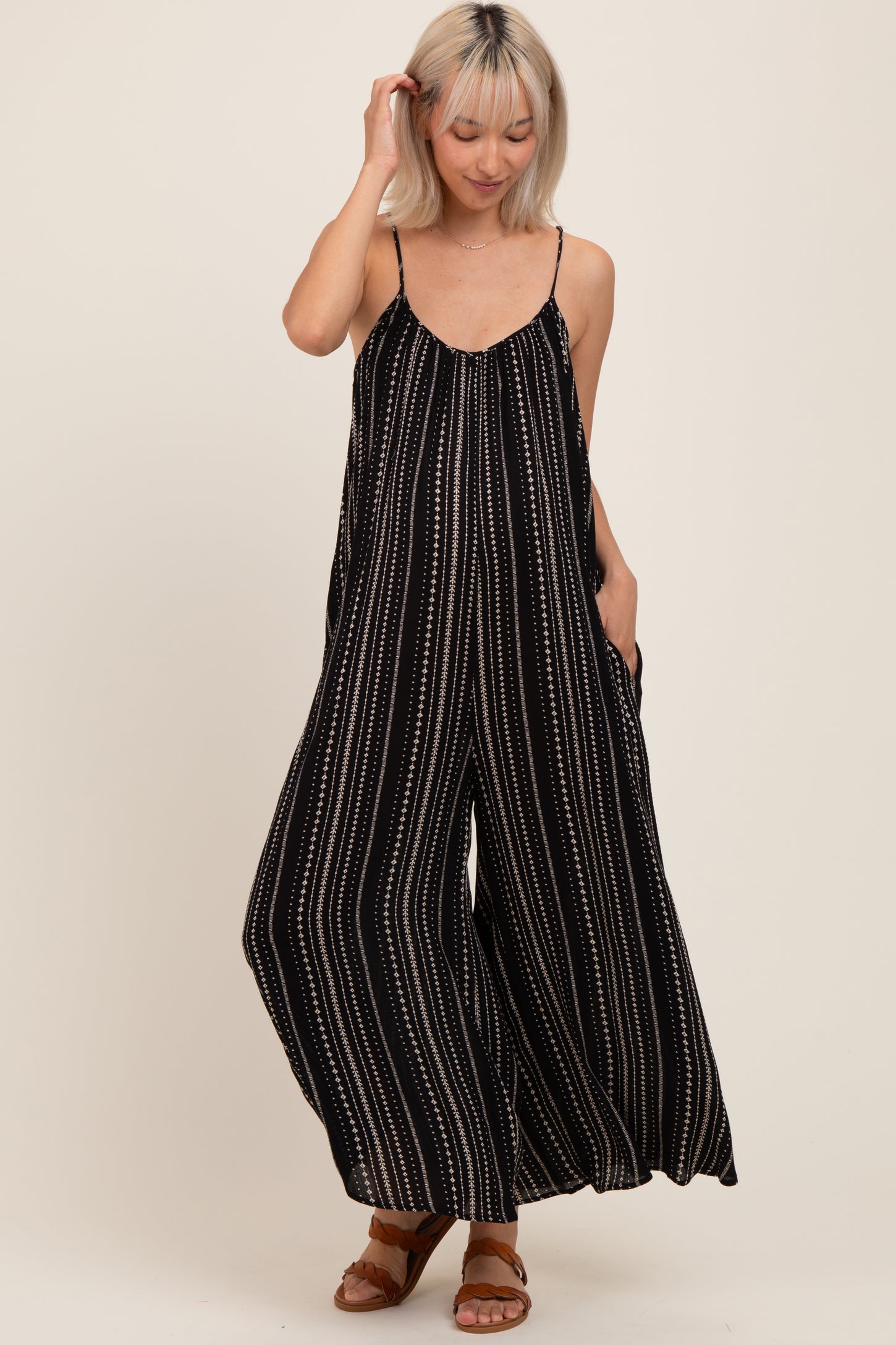 woman wearing a black and white striped maternity jumpsuit with wide legs and pockets