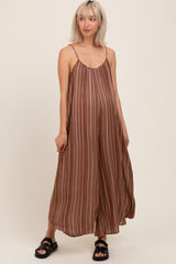 woman wearing a brown striped maternity dress with spaghetti straps and a relaxed fit, holding her baby bump