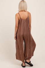 woman wearing a brown patterned maternity jumpsuit with wide legs, showing the back and straps