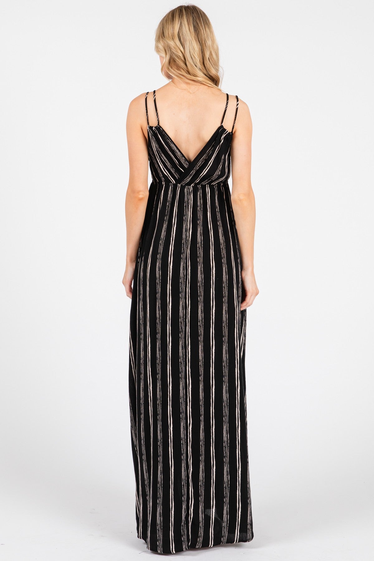 woman wearing a black and white striped maxi dress with thin adjustable straps viewed from the back