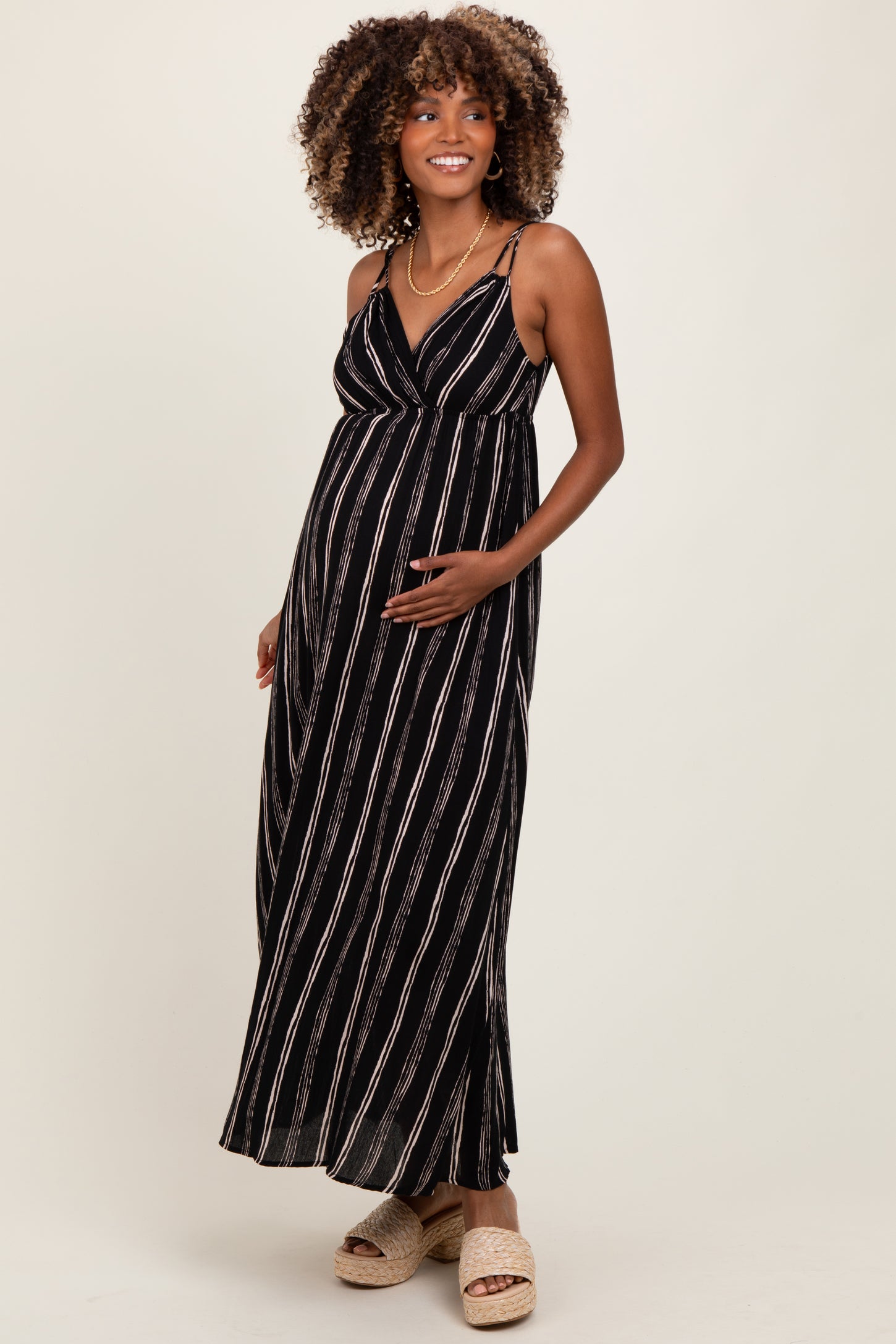 woman wearing a black and white striped maternity maxi dress and holding her baby bump