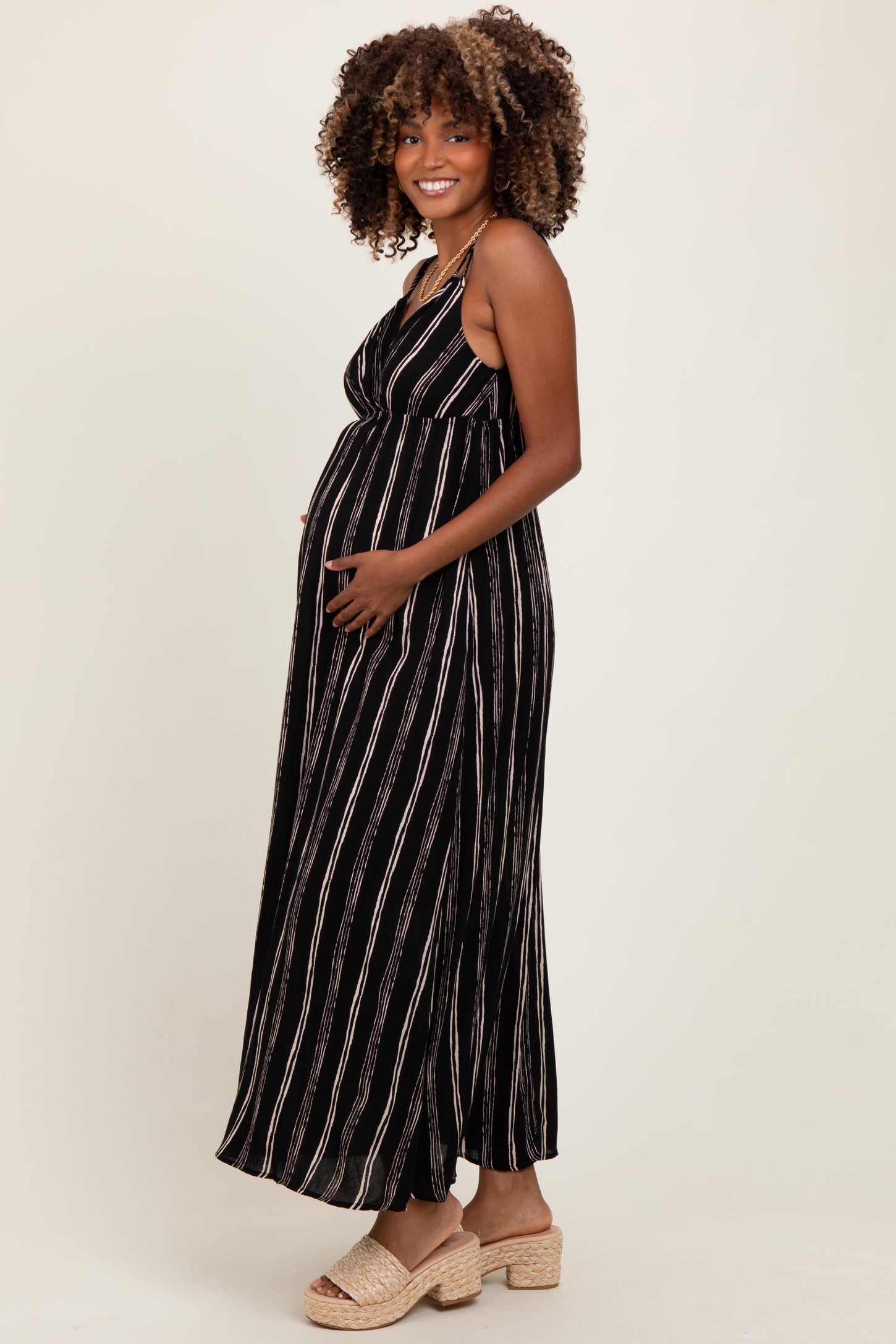 woman wearing a black and white striped maternity maxi dress and holding her baby bump