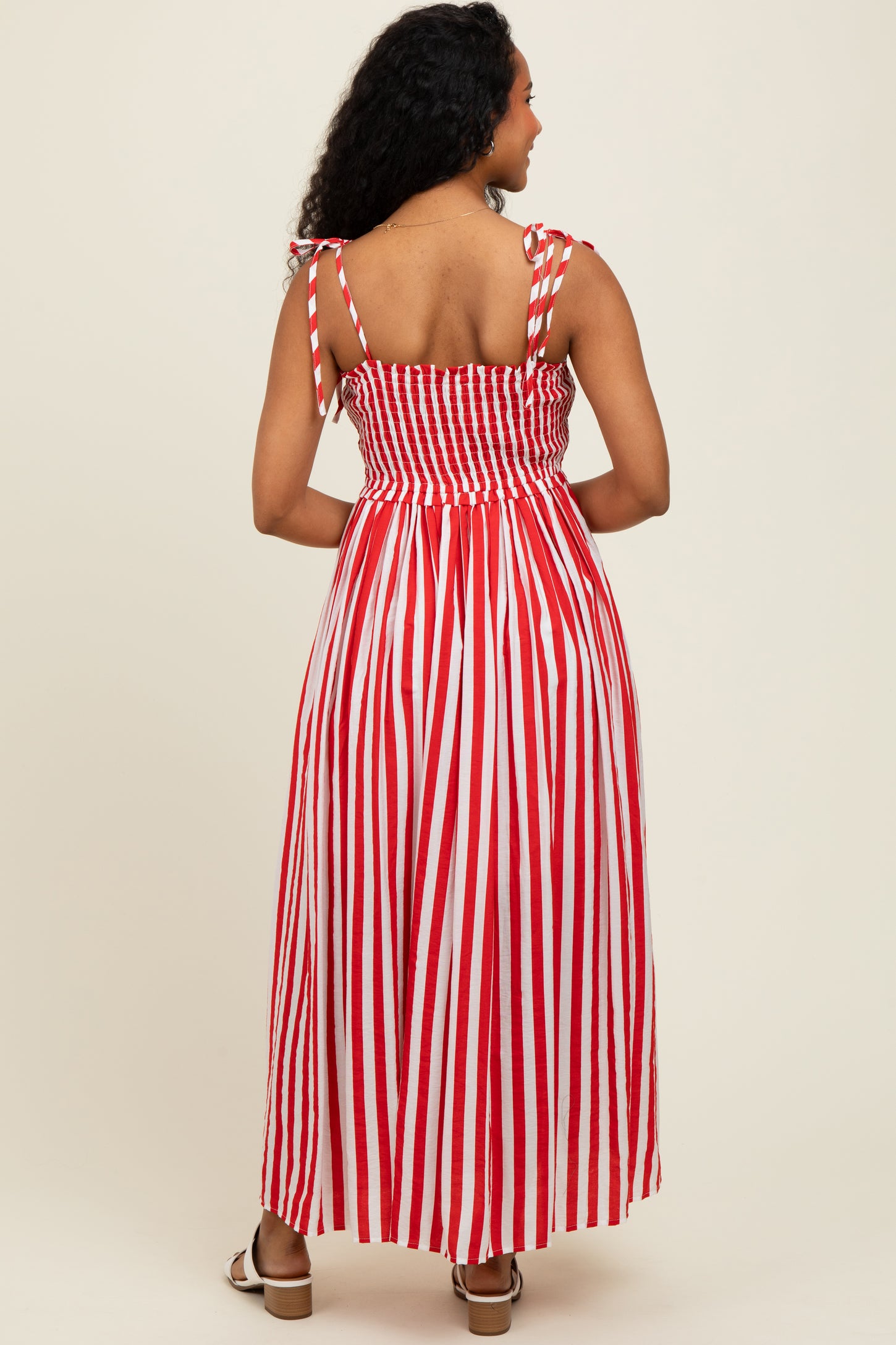 woman wearing a red and white striped maxi dress with smocked bodice and tied straps, shown from the back