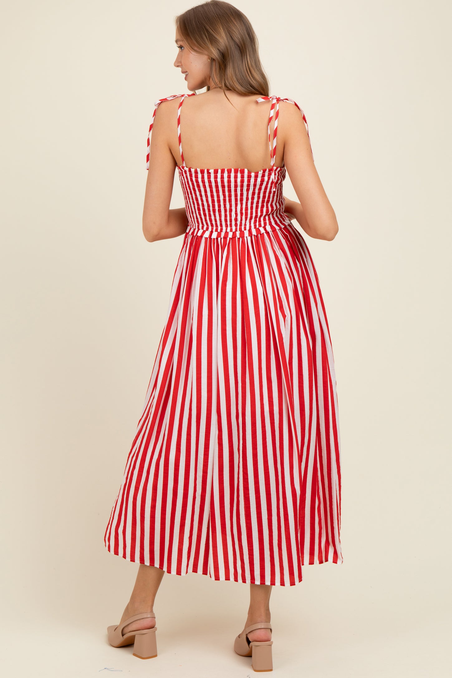 woman wearing a red and white striped maternity dress with smocked back and tie shoulder straps