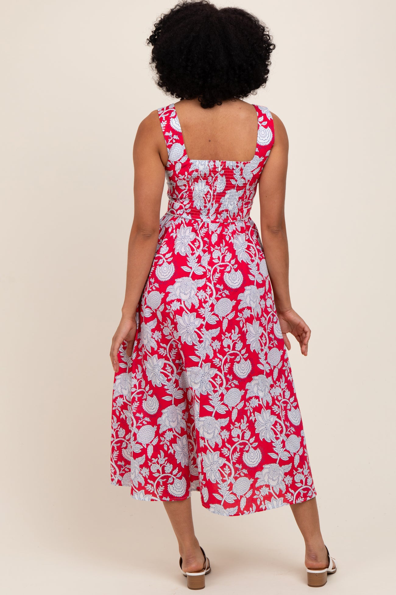 woman wearing a pink and white floral maxi dress with a smocked back and wide straps, shown from the back