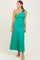 woman wearing a green one-shoulder maxi dress with a flower detail on the shoulder, standing confidently